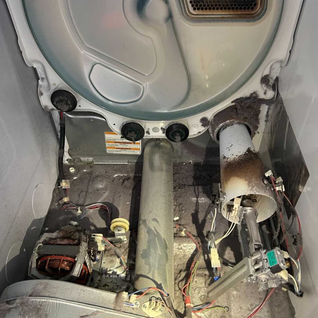 Interior view of a Whirlpool dryer showing worn idler pulley, stretched drum belt, and accumulated lint, highlighting the need for repair services in Brecksville, Ohio.